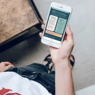 Hand holding a smartphone displaying the GroupS mobile app interface with informational cards on a green background.