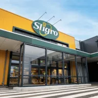 Exterior of Sligro wholesale store with yellow facade, green circular logo, and glass entrance doors with steps leading to the entrance.