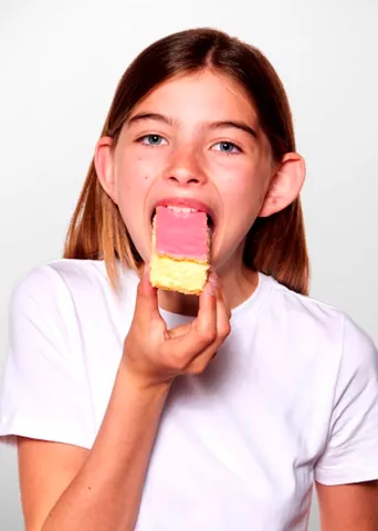 Girl in white t-shirt eating a tompouce from Hema