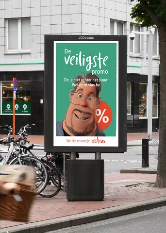 Street digital display showing Ethias insurance ad with an AI cartoon character on green background, featuring Dutch text "De Veiligste promo" (= The Safest Promo) and the Ethias logo.