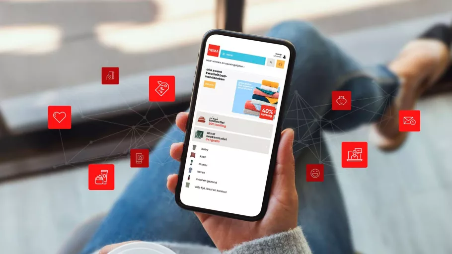 Smartphone showing the website of Hema held in woman's hand with red icons around it