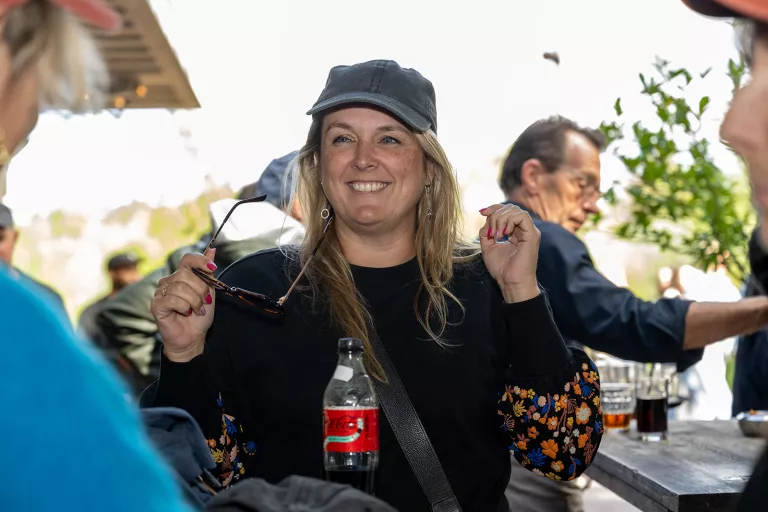 Smiling woman from Springbok Agency in a casual setting, wearing a cap and holding sunglasses. 