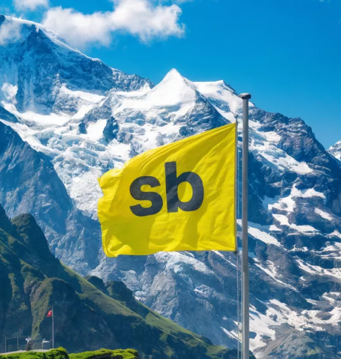 Header image to announce the launch of Springbok Agency Switzerland, showing a Swiss snowy mountain range and a yellow Springbok flag. 